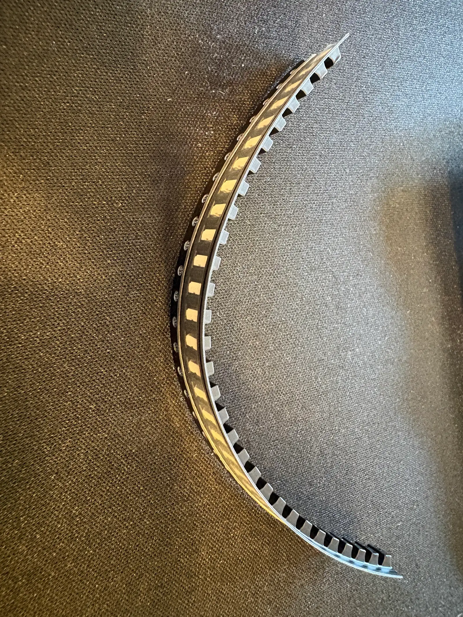 A curled black plastic carrier strip holding the LEDs, on a fabric surface.